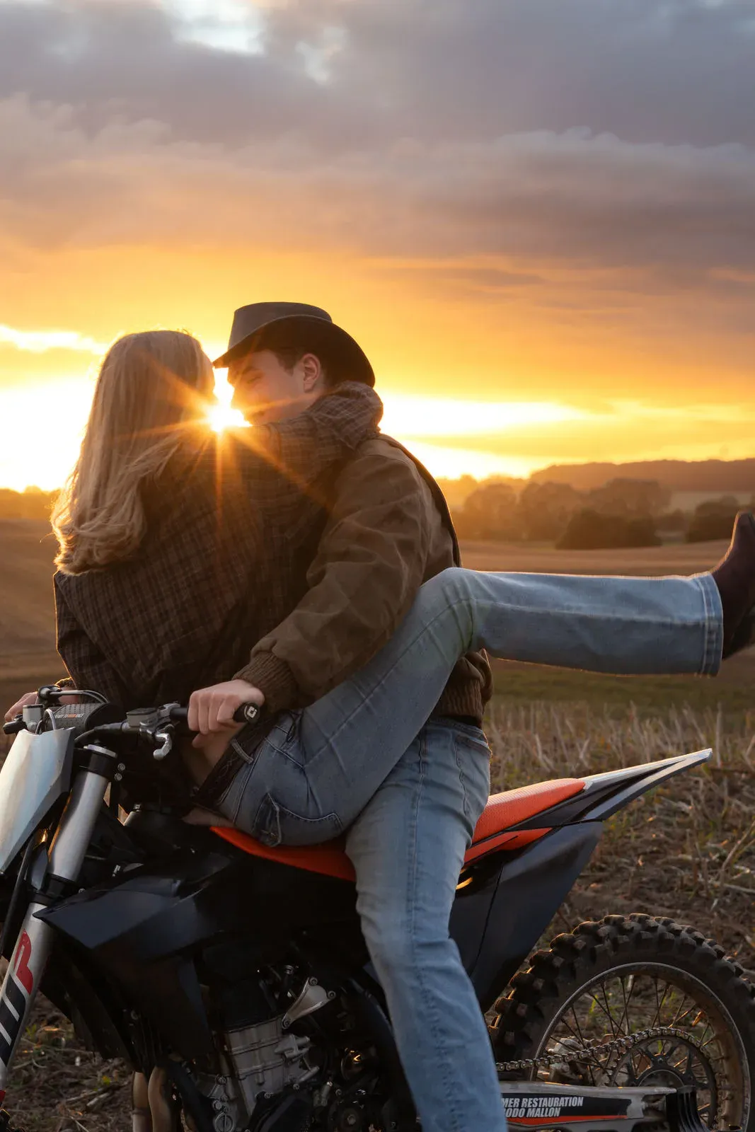 Paar küsst sich auf dem Motorrad vor dem Sonnenuntergang