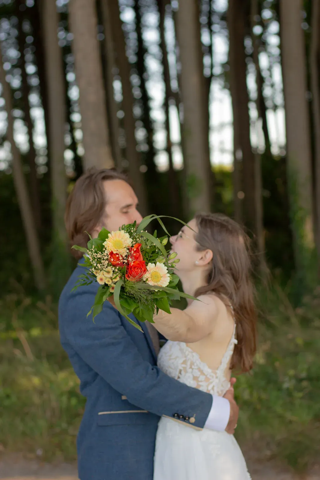 Paar umarmt sich im Wald, sie hält einen bunten Blumenstrauß